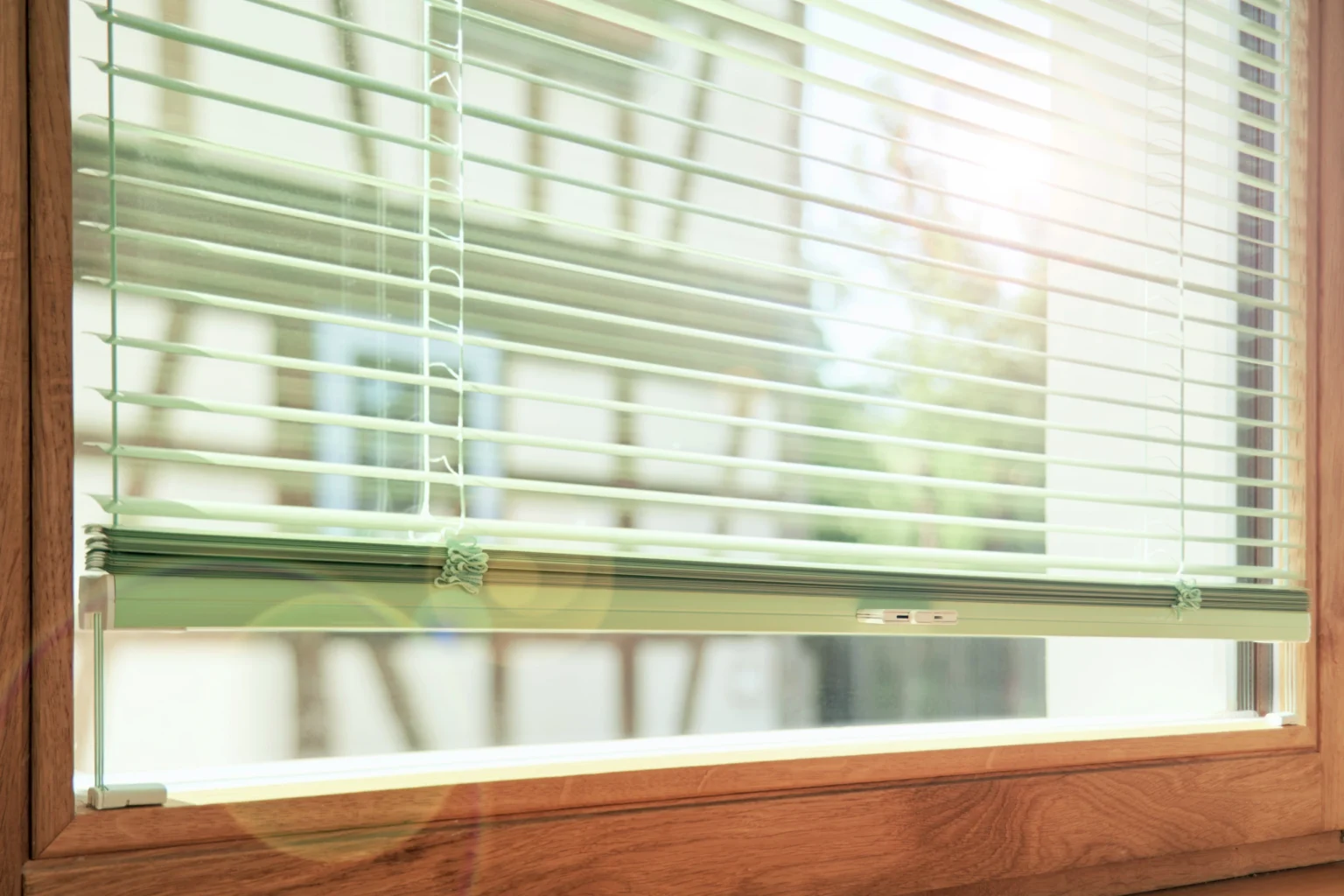 Elegantes Holzfenster mit Alu-Jalousien und Fachwerkhaus gegenüber