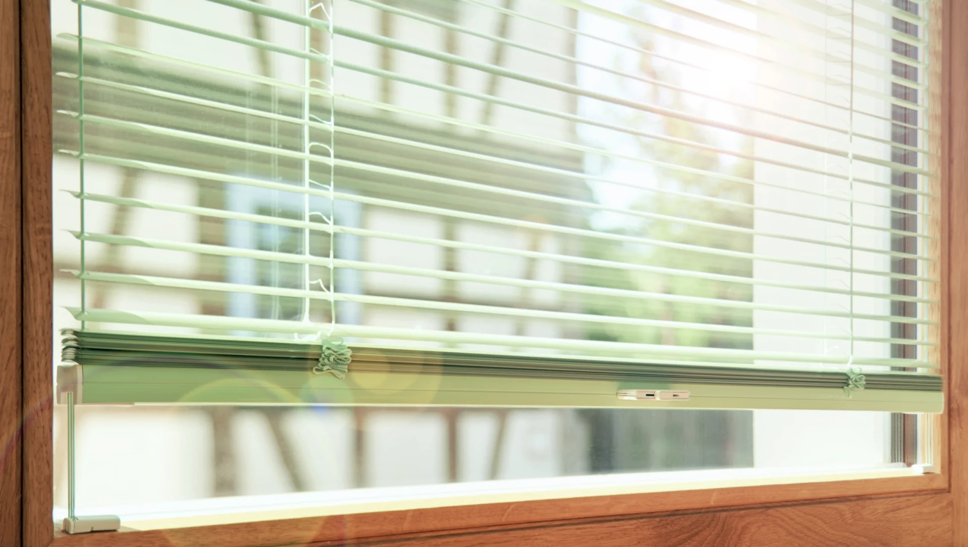 Elegantes Holzfenster mit Alu-Jalousien und Fachwerkhaus gegenüber