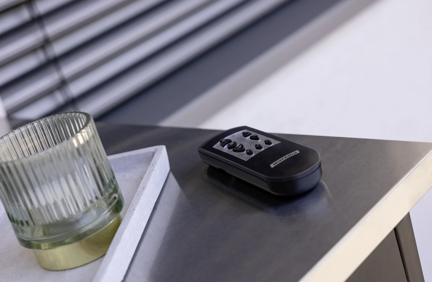 Schwarzer Handsender für die Sonnenschutzsteuerung auf modernem Tisch liegend