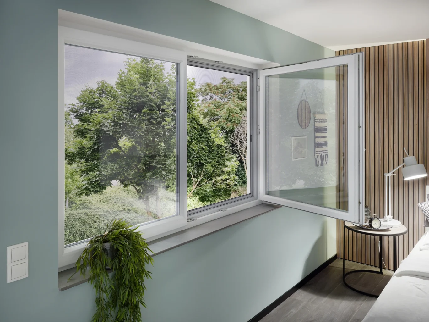 Modernes geöffnetes Fenster mit Blick ins Grüne und Dekoration im Zimmer