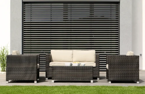 Moderne Outdoor-Sitzgruppe aus Rattan vor einem Fenster mit Jalousien