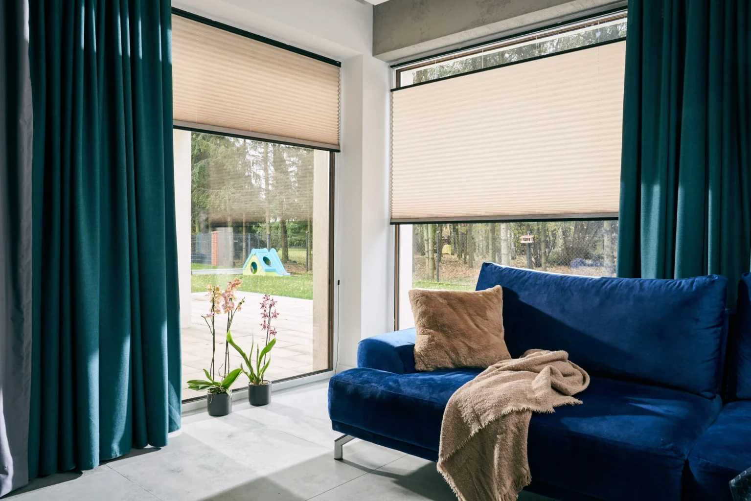 Modernes Wohnzimmer mit blauen Sofa und großen Fenstern