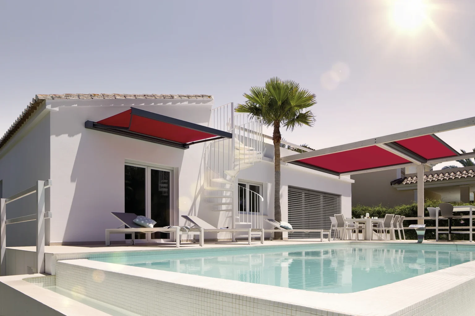 Moderne Villa mit Pool und roten Markisen bei Sonnenschein