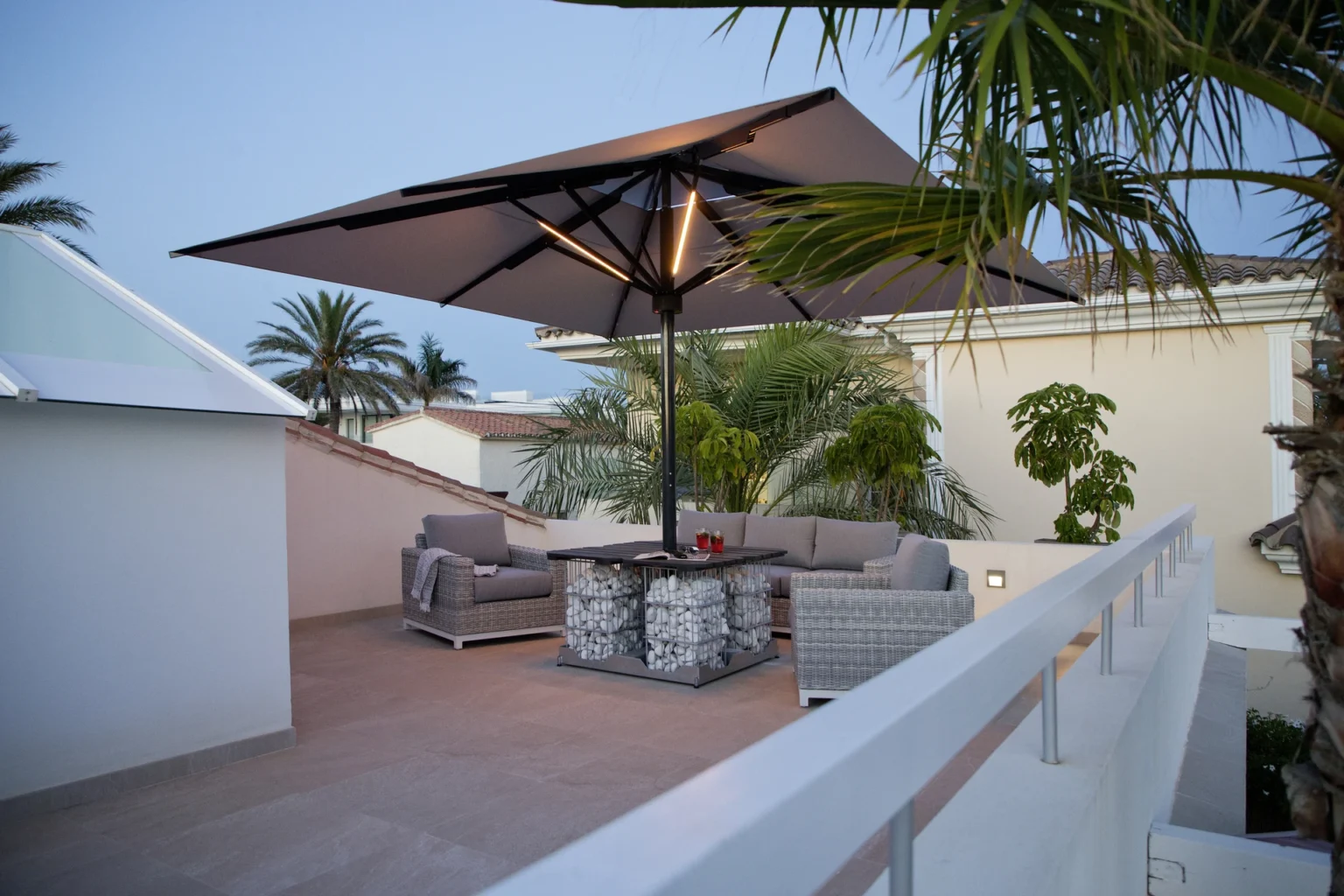 Moderne Dachterrasse mit stilvollen Möbeln und großem Sonnenschirm bei Abenddämmerung