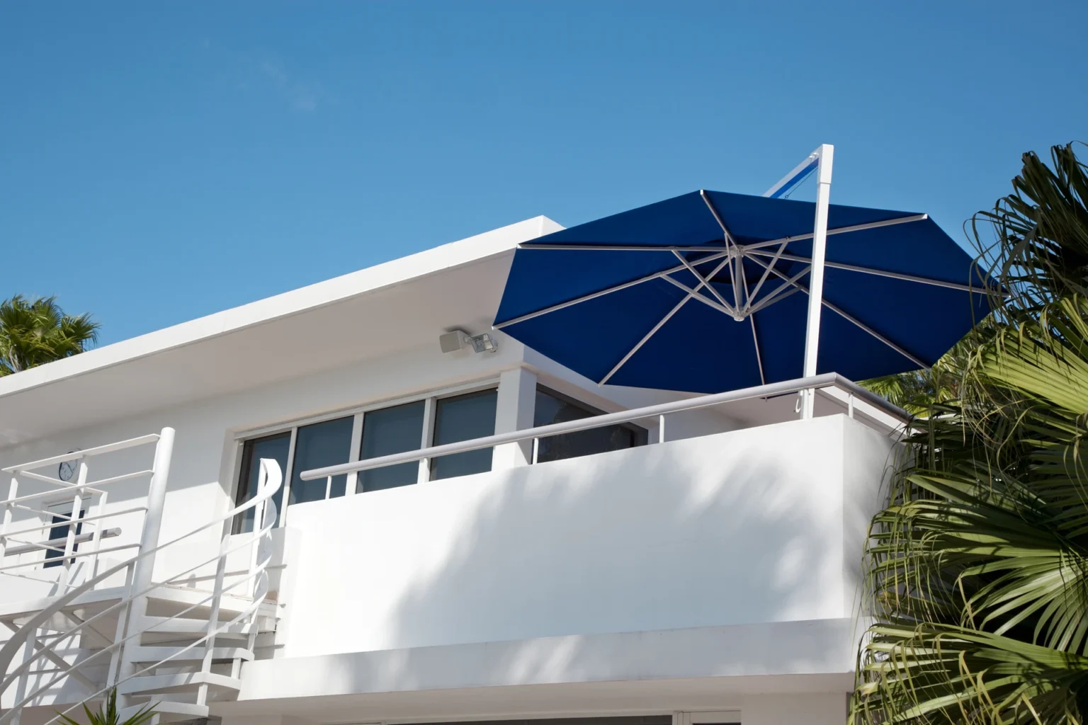 Moderne Villa mit blauem Sonnenschirm auf dem Balkon