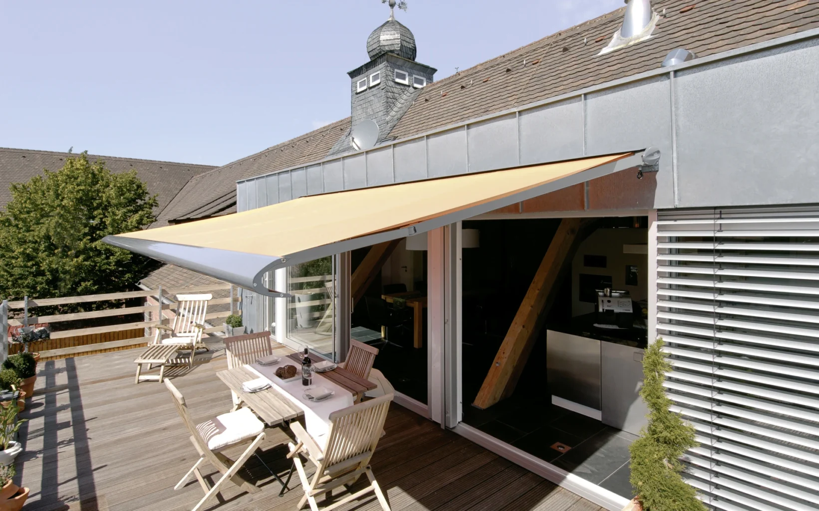 Terrasse mit Markise und Gartenmöbeln an einem sonnigen Tag